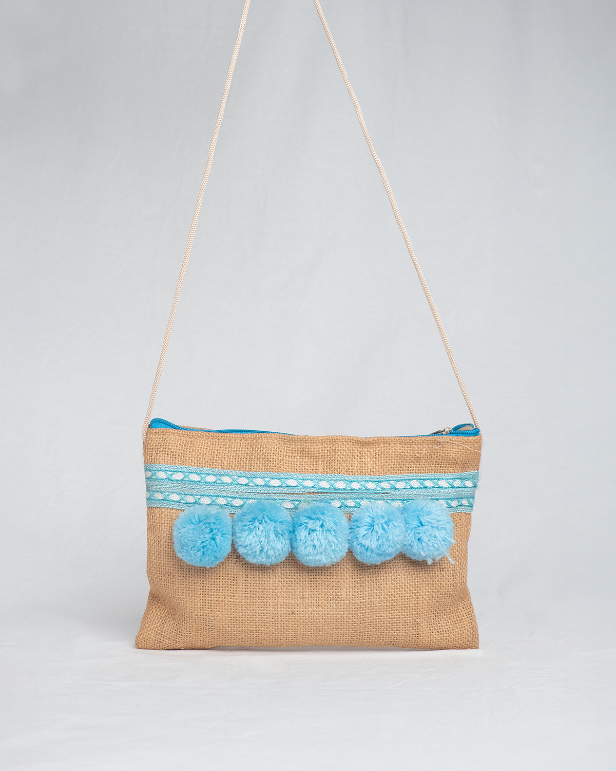 Bolso artesanal con pompones turquesa y cinta de seda.